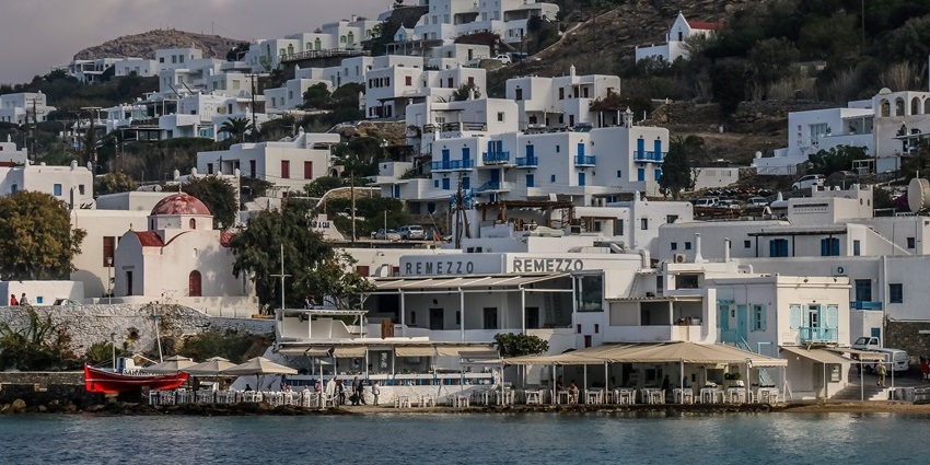 Enjoying seaside dining with white Cycladic buildings is one of the top things to do in Mykonos in June.
