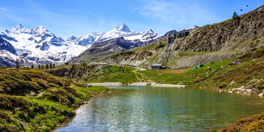 Beautiful lake at Sunnegga Paradise with snow-covered mountains in the background.