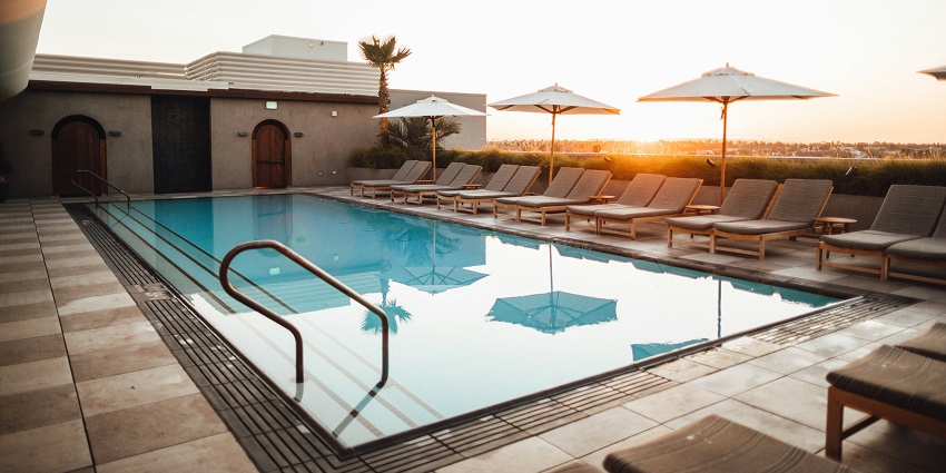 Indoor swimming pool with clear blue water and sunbathing benches along the side.
