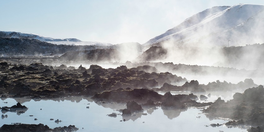 Steaming blue geothermal waters surrounded by volcanic rocks in Iceland.