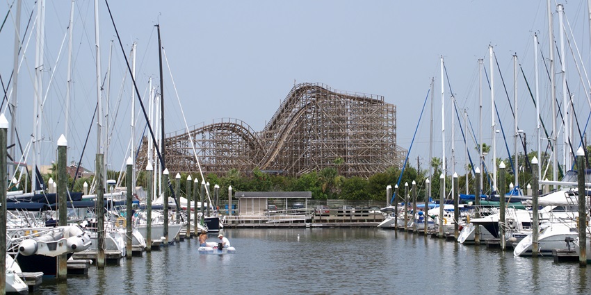 Marina with sailboats docked in the front and a large roller coaster on the back at Kemah.