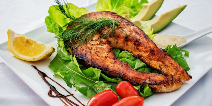 Savoring a freshly prepared fish dish on a plate, showcasing Swahili coastal flavors.
