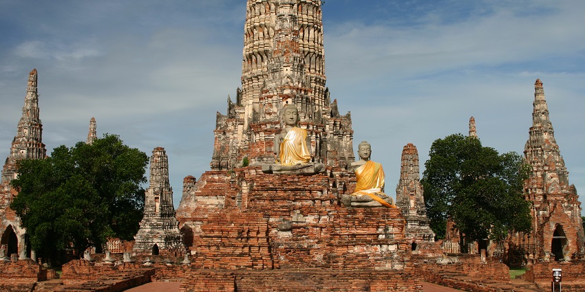 The ancient temple ruins and stupa in Ayutthaya, Thailand, framed by trees and sky.