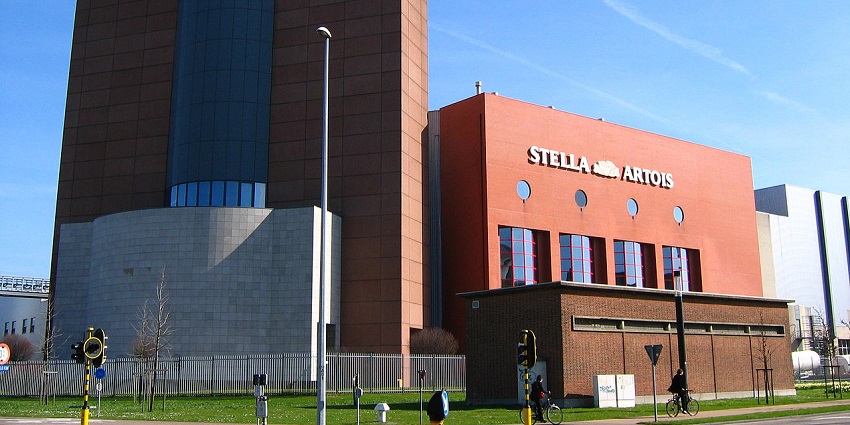 Stella Artois brewery building in Leuven with a red brick facade under a blue sky.
