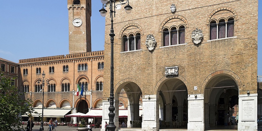 Piazza dei signori e palazzo dei trecento in treviso with unique tall street lamps and flags.