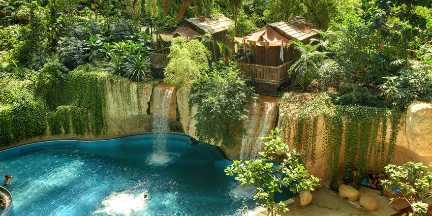 Interior view of Tropical Islands Resort with palm trees, pools, and beach‑style seating.