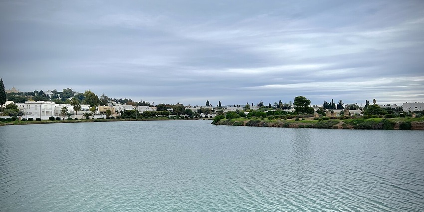 Water body at the Punic Ports site in Carthage, Tunisia, surrounded by greenery and houses.