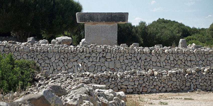 Ancient stone structure with stacked rocks and a T-shaped monument surrounded by greenery.