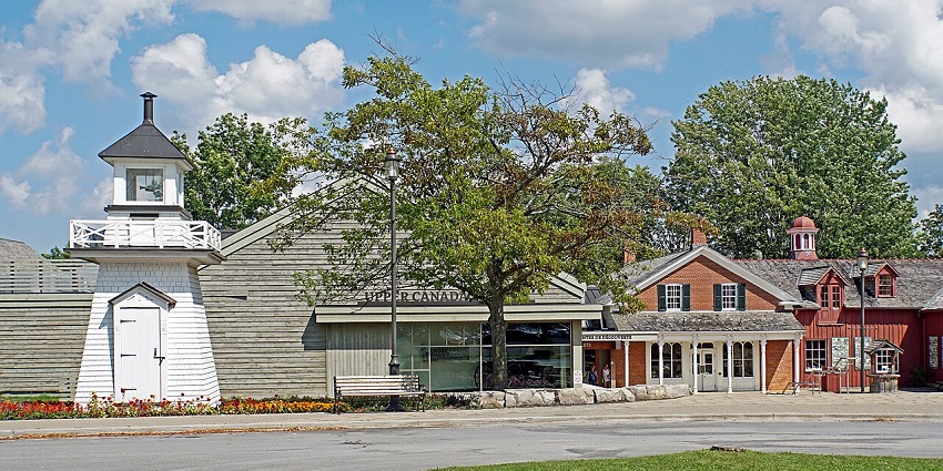 The wooden arch marks the entrance to Upper Canada Village, with old-style houses around.
