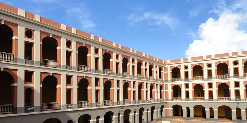 Spacious open courtyard surrounded by a multi-story building with archways and columns.
