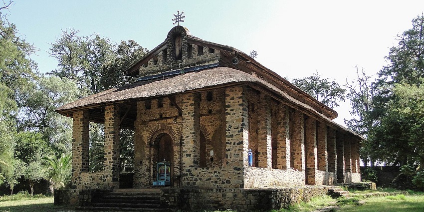 Debris Berhan Selassie Church with traditional Ethiopian architecture, entrance, and greenery.
