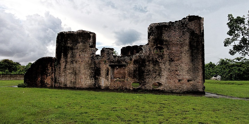 Ruins of Fort Zeelandia with old architecture, broken walls, a window, green grass and trees.
