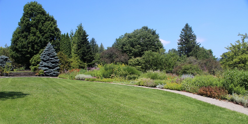 Berkshire Botanical Garden with finally cut green grass, plants and a small walking pathway.