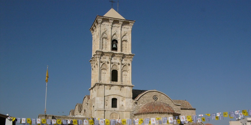 Church of Saint Lazarus in Larnaca with visitors near its arched entrance and bell tower.