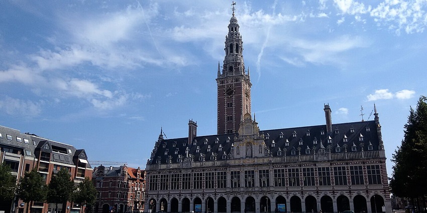 Leuven University Library with an ornate facade and tower, set against a clear blue sky.
