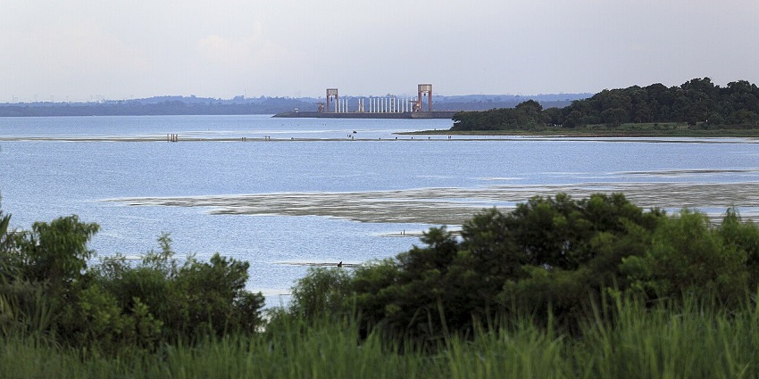 Itaipú dam in Paraguay with a large water body, green shorelines, trees, and distant dam structures.