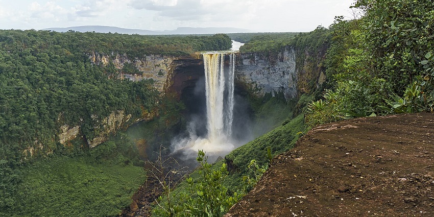 Visiting the Kaieteur Falls with water cascading from a cliff surrounded by dense greenery, one of the things to do in Guyana.
