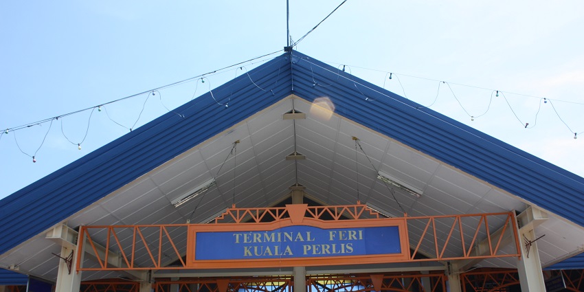 Blue and white roof of Kuala Perlis Jetty Terminal with terminal name visible on the facade.