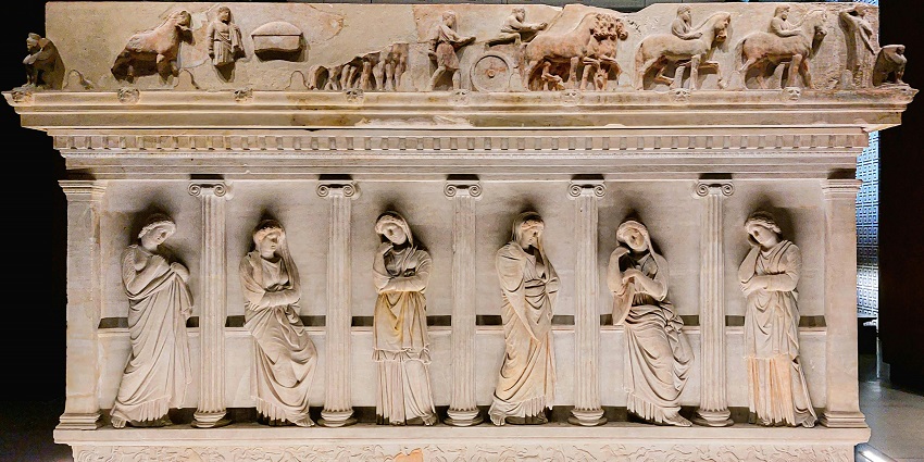Inside a museum of history with detailed and intricate carvings on an old rock structure.
