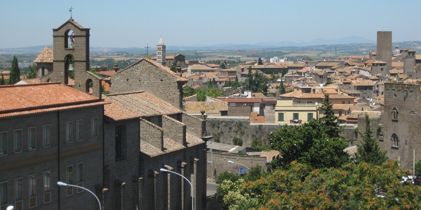 Viterbo with Christian crosses on top of the multiple buildings and multiple street lights.