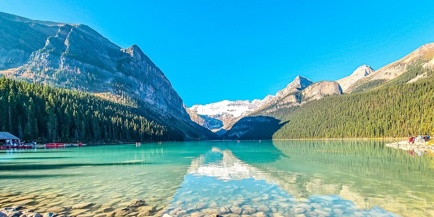 Scenic lakeside trail surrounded by trees and peaceful picnic spots along the water.