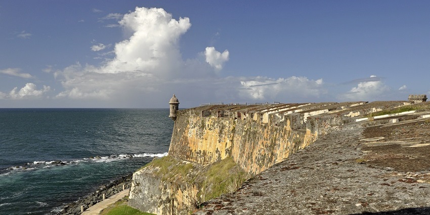 Weathered stone fort on a cliffside overlooking the ocean under a bright sky, one of the best things to see in Old San Juan.