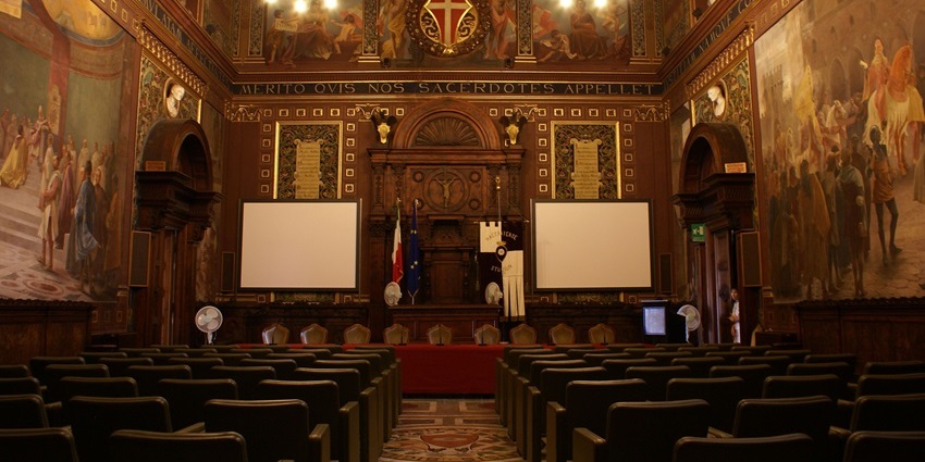 Elegant hall at the University of Macerata with decorative ceiling, lights, and chairs.