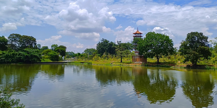 Wide view of Chinese Garden from Japanese Garden with calm water and dense greenery.