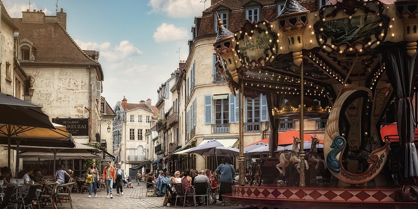 Village square at night with cafes, outdoor seating, and a horse ride attraction for kids.