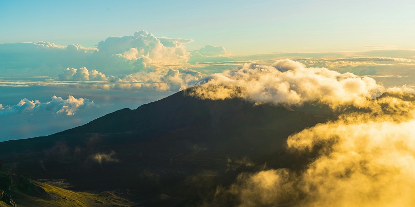 Sunrise view from the summit of Haleakalā National Park with colorful sky and mountain landscape.
