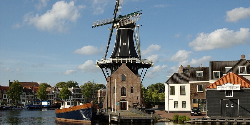 Molen De Adriaan windmill illuminated overlooking the city lights.