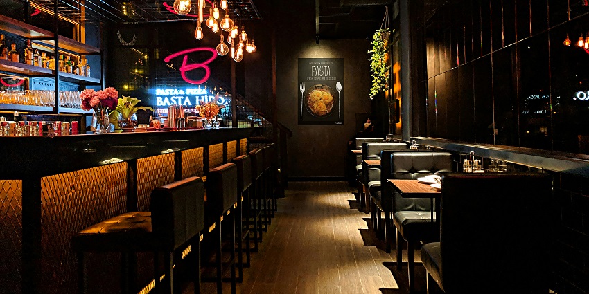 A dimly lit bar interior with wooden chairs and a cosy atmosphere at the counter.