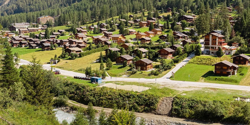 Zinal village from above, with buildings and houses surrounded by greenery and mountains, one of the places to visit near Zermatt.
