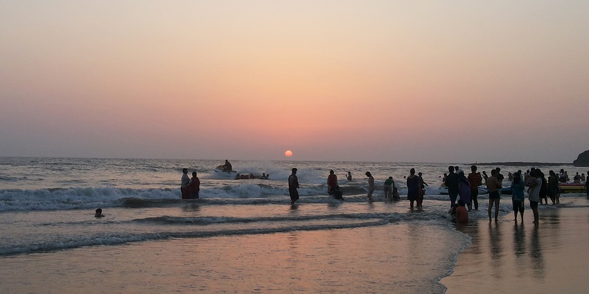 Beautiful sunset at Alibaug Beach with silhouettes of people enjoying the beach peacefully, one of the best places to visit near Navi Mumbai in one day.