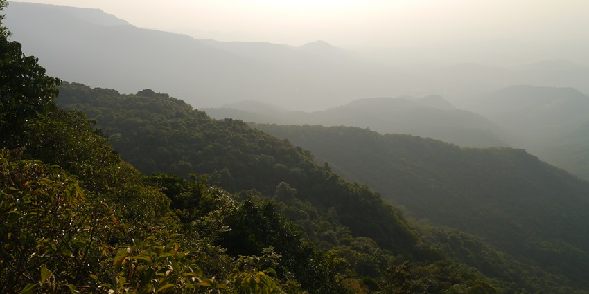 Scenic view from Amboli Ghat in Maharashtra, India, showing lush green hills and sky.