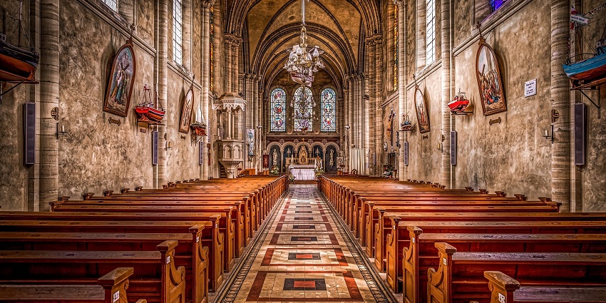 Interior view of St. John’s Church in Anand, Gujarat, with arched windows and wooden pews.