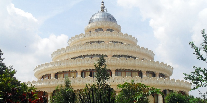 Art of Living International Ashram and its lotus-shaped dome against the backdrop of a cloudy sky.
