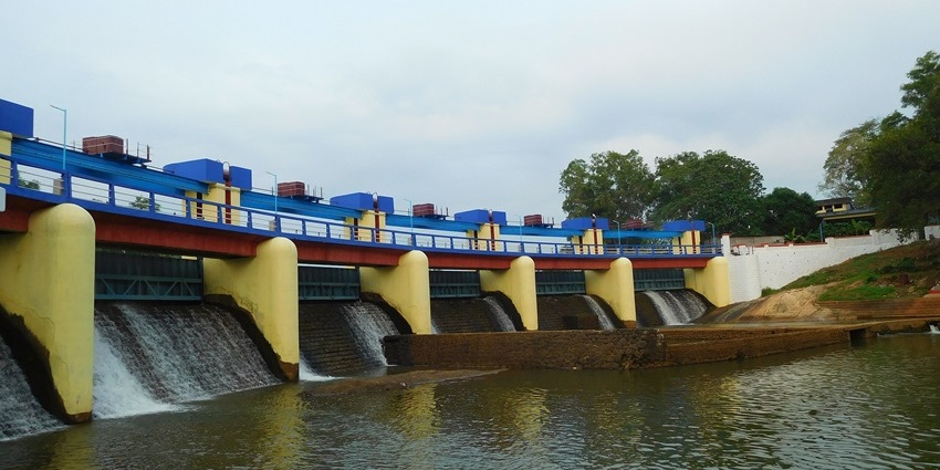 Aruvikkara dam with calm water, spillway, and surrounding greenery in Kerala.
