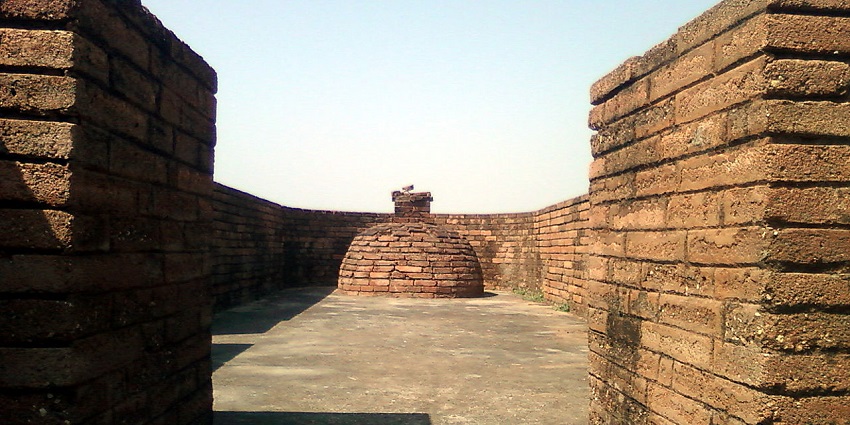 Ancient brick walls and small circular brick buildings under blue sky view.