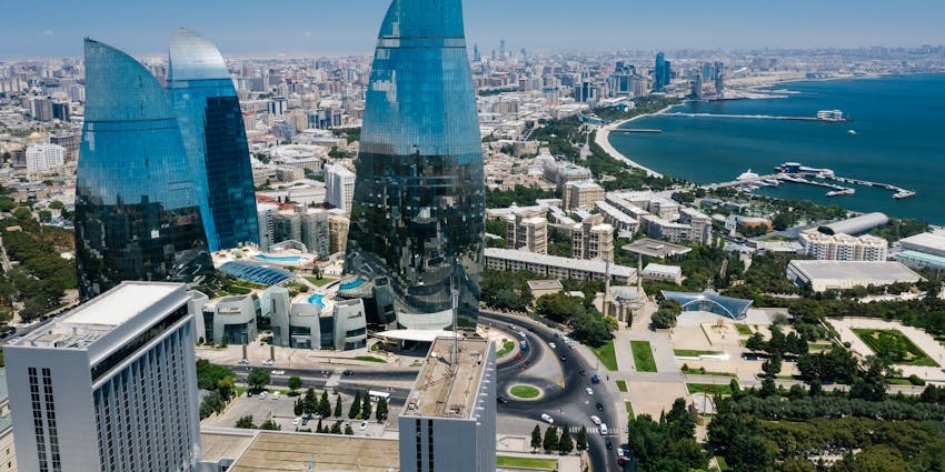 Aerial view of Baku showing a mix of modern architecture, coastal roads, and urban layout.
