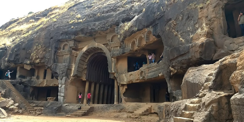 Entrance to the Bhaja caves in Maharashtra, with people visiting and entering the caves.