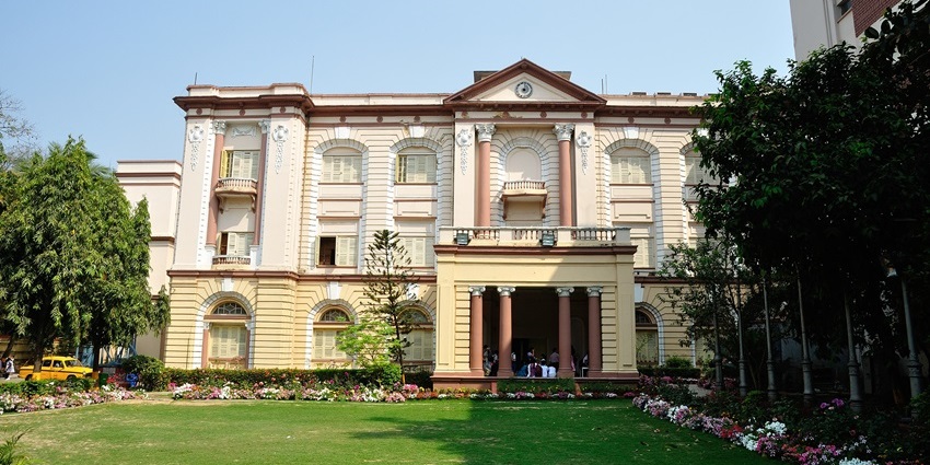 Birla Industrial and Technological Museum with unique flowers, green grass, and tall trees.
