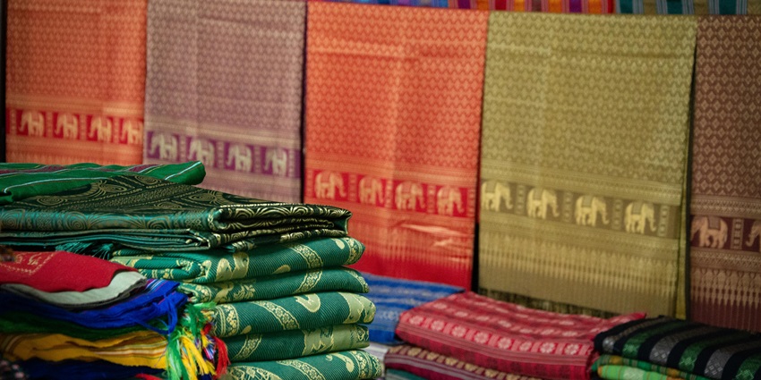 Colorful traditional fabrics are displayed at the Bishnupur market with vibrant textures and patterns.