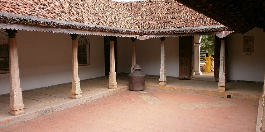 Traditional Tamil courtyard house with tiled roof, stone pillars, and open central space.