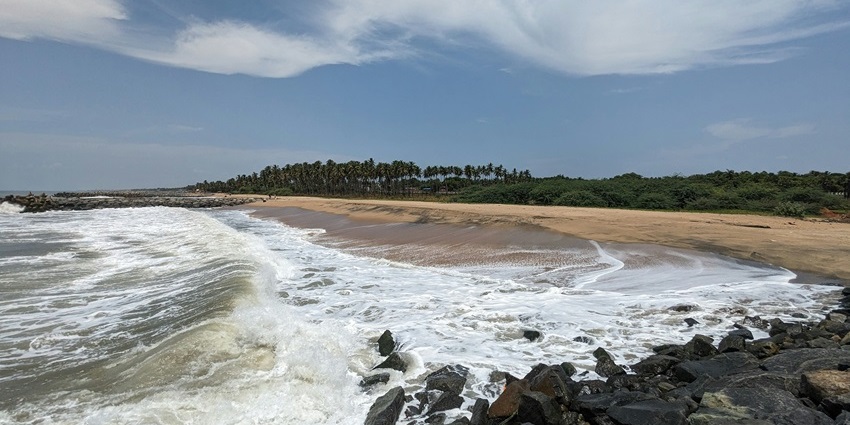 Waves crashing on rocks along the sandy shoreline of Digha Beach in West Bengal.