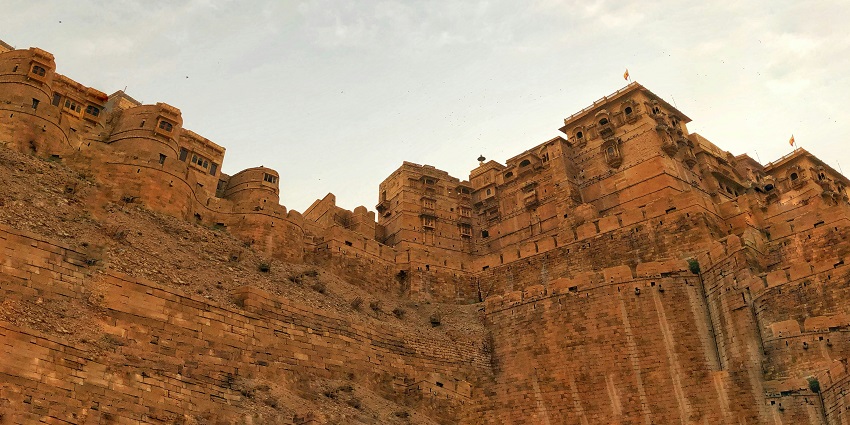 Jaisalmer Fort glows in the warm evening light with clear skies in the background.
