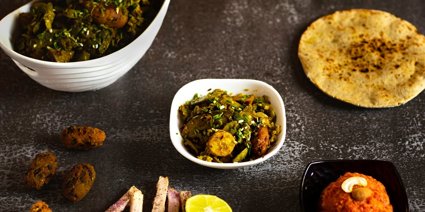Traditional Gujarati thali with various vegetarian dishes and accompaniments.
