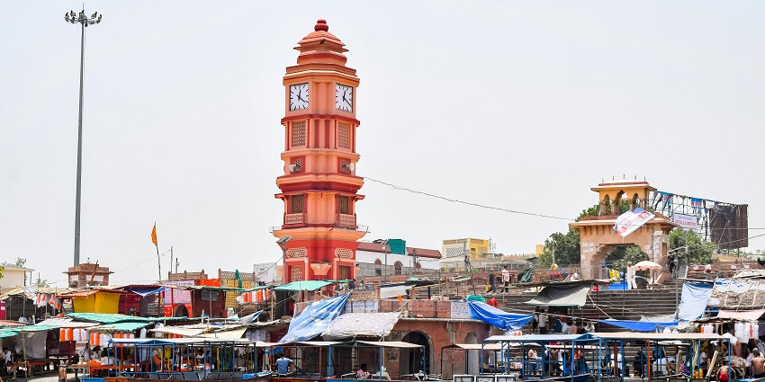 Wooden boats docked at Garhmukteshwar ghat with the iconic clock tower in the backdrop.