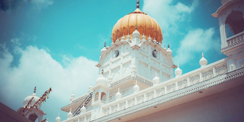 Orange dome and white structure of Gurdwara Lakhi Jungle Sahib under open sky, one of the places to visit near Damdama Sahib.