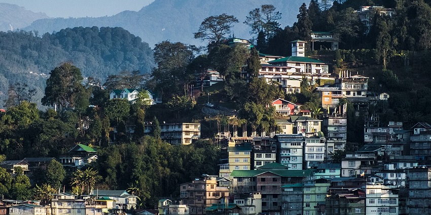 Panoramic view of Gangtok city with colorful buildings and surrounding mountain landscape.